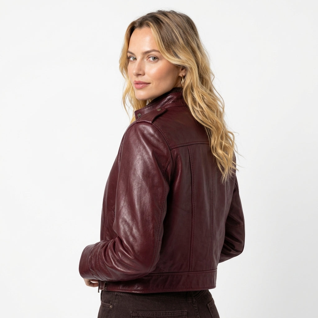 Maroon women's leather jacket featuring a snap-button collar, front zipper pockets, and stylish stitching details